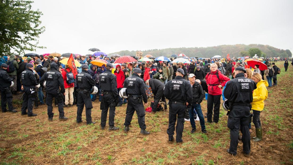 Teilnehmer der Demonstration gegen die Rodung des Hambacher Forsts warten im Regen vor einer Polizeikette. Foto: Christophe Gateau