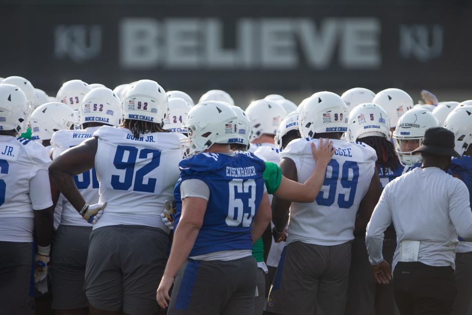 The word "believe" is seen in the background as Kansas players, including redshirt sophomore defensive lineman Tommy Dunn Jr. (92), huddle up at the beginning of a fall camp practice this year.