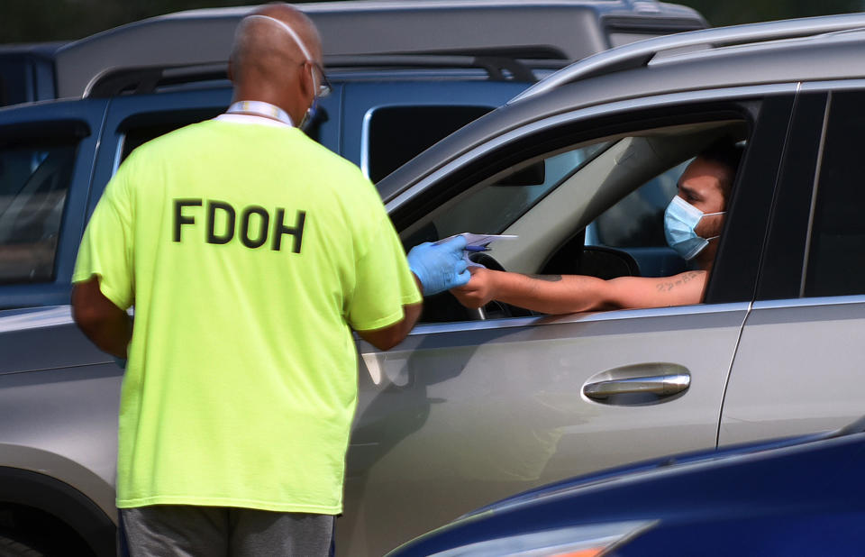 KISSIMMEE, FLORIDA, UNITED STATES - 2020/07/14: A health department worker checks in a man wearing a mask to be tested for COVID-19 at a drive through testing site at Osceola Heritage Park.  Florida continues to be a hot spot for coronavirus cases and the demand for testing also remains high with over 600 people visiting this site today. (Photo by Paul Hennessy/SOPA Images/LightRocket via Getty Images)