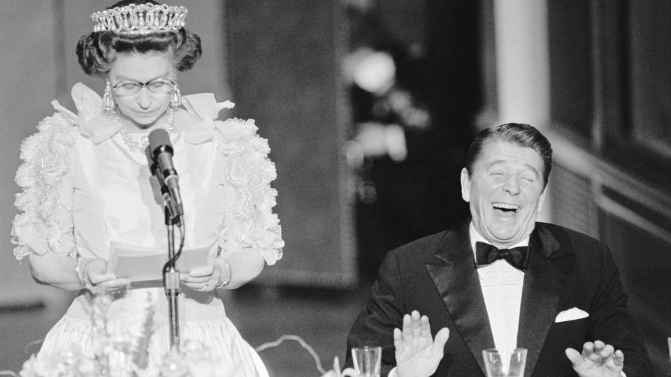 President Reagan laughs following a joke by Queen Elizabeth II, who commented on the lousy California weather she has experienced since her arrival to the States. The British Queen is delivering a brief address during a state dinner held at the De Young Museum in San Francisco.