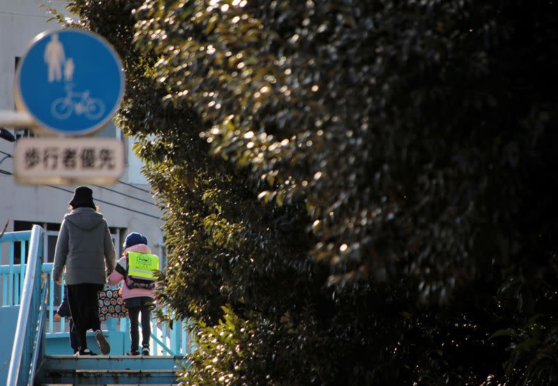 An elementary school student and her mother walk toward her school in Tokyo, Japan