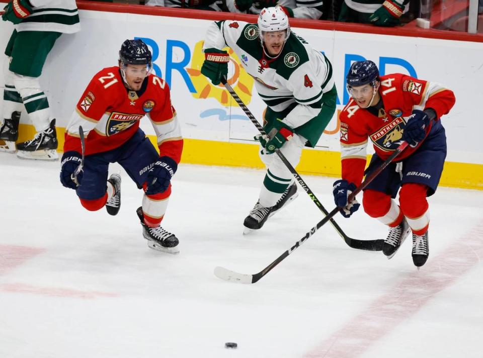 Florida Panthers left wing Grigori Denisenko (14) passes the puck as Minnesota Wild defenseman Jon Merrill (4) defends in the second period at FLA Live Arena in Sunrise, FL on Saturday, January 21, 2023.