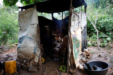 A family eats dinner in a makeshift kitchen outside a house in Boucan Ferdinand, Haiti, October 7, 2018. REUTERS/Andres Martinez Casares