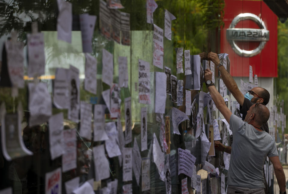 FILE - In this May 29, 2020, file photo, Nissan workers fix leaflets on a car dealerships window during a protest in Barcelona, Spain. Nissan Chief Executive Makoto Uchida told shareholders Monday, June 29, 2020 he is giving up half his pay as the Japanese automaker sank into the red amid plunging sales and plant closures in Spain and Indonesia. (AP Photo/Emilio Morenatti, File)