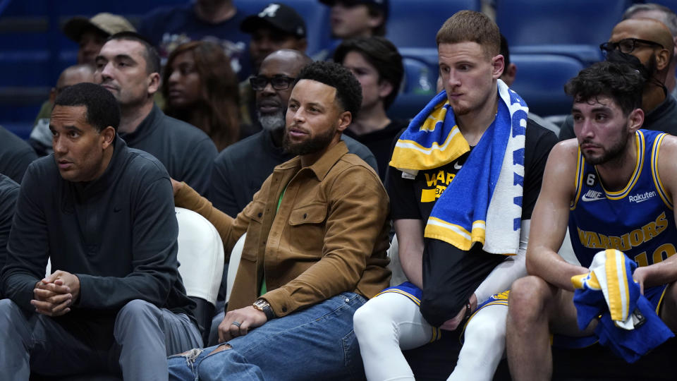 Golden State Warriors guard Stephen Curry, in street clothes because he did not play, sits on the bench in the second half of an NBA basketball game against the New Orleans Pelicans in New Orleans, Monday, Nov. 21, 2022. The Pelicans won 128-83. (AP Photo/Gerald Herbert)