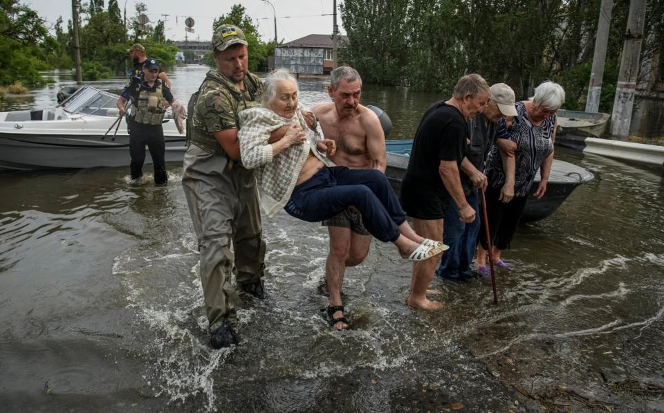 Rescuers evacuate local residents from a flooded area after the Nova Kakhovka dam breached - Reuters