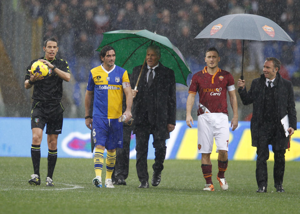 From left referee Andrea de Marco, Parma's Alessandro Lucarelli, and AS Roma forward Francesco Totti, second from right, check the pitch before the start of an Italian Serie A soccer match between AS Roma and Parma at Rome's Olympic stadium, Sunday, Feb.2, 2014. The match was suspended a few minutes after the start due to bad weather conditions. (AP Photo/Alessandra Tarantino)