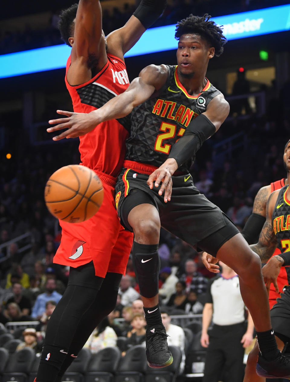 Atlanta Hawks guard Cam Reddish, right, dishes off while guarded by Portland Trail Blazers center Hassan Whiteside, left, during the first half of an NBA basketball game Saturday, Feb. 29, 2020, in Atlanta. (AP Photo/John Amis)