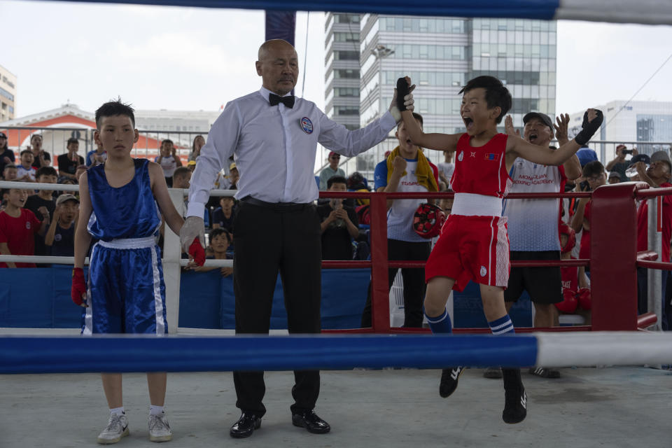 Twelve-year-old Gerelt-Od Kherlen, in red, reacts after winning a bronze medal boxing match on Sukhbaatar Square in Ulaanbaatar, Mongolia, Tuesday, July 2, 2024. Growing up in a Ger district without proper running water, Gerelt-Od fetched water from a nearby kiosk every day for his family. Carrying water and playing ball with his siblings and other children made him strong and resilient. (AP Photo/Ng Han Guan)