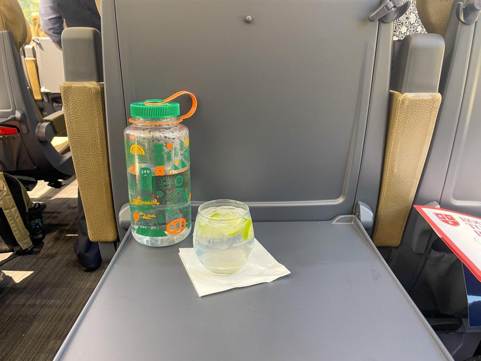 A water bottle and wine glass sit on the tray table of the train.