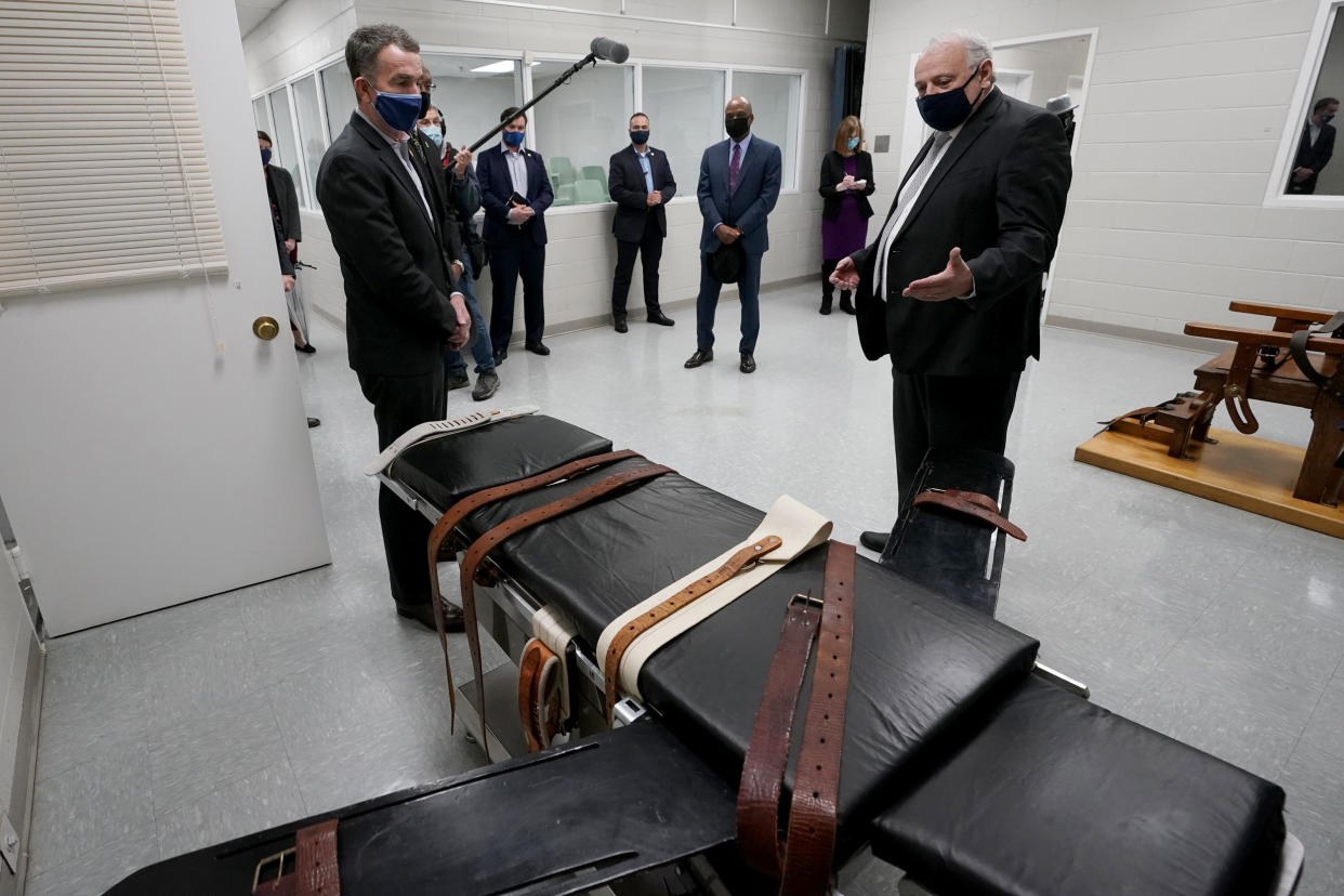 IMage: Virginia Gov. Ralph Northam looks at a gurney at Greensville Correctional Center with Operations Director George Hinkle on March 24, 2021. (Steve Helber / AP)