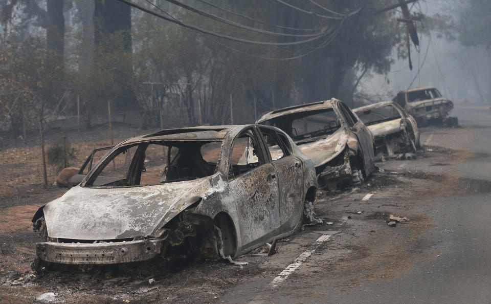 FILE - The burned hulks of cars abandoned by their drivers sit along a road in Paradise, Calif., Nov. 9, 2018. The Camp Fire bears many similarities to the deadly wildfire in Hawaii. Both fires moved so quickly residents had little time to escape. (AP Photo/Rich Pedroncelli, File)