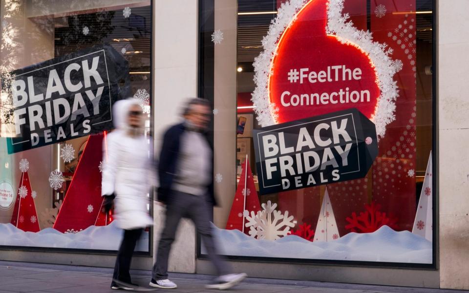 People walk past a Black Friday sign in Oxford Street, London - AP Photo/Alberto Pezzali