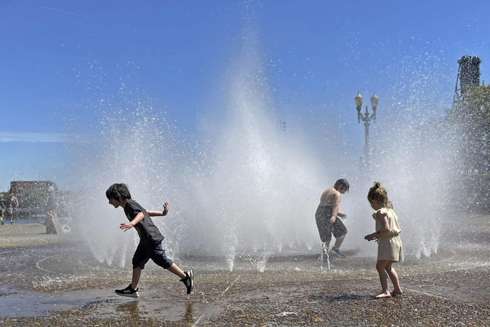 Children play in a fountain to cool off in downtown Portland, Ore., Friday, May 12, 2023. An early May heat wave this weekend could surpass daily records in parts of the Pacific Northwest and worsen wildfires already burning in western Canada, a historically temperate region that has grappled with scorching summer temperatures and unprecedented wildfires fueled by climate change in recent years. (AP Photo/Claire Rush)