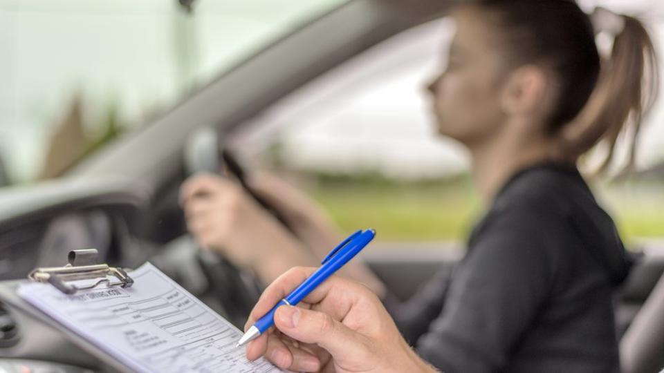 Joven conduciendo al lado de un examinador.