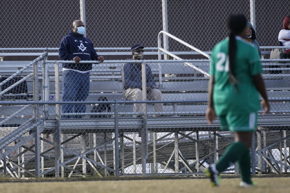 Larry Brown, left, and his father, John Brown, watch Larry's daughter, Justys Glenn, right, play in a soccer game, Wednesday, Sept. 30, 2020, in Indianapolis. He didn’t die after contracting COVID-19, but he’s coming to terms with the fact that his life might never be the same. (AP Photo/Darron Cummings)