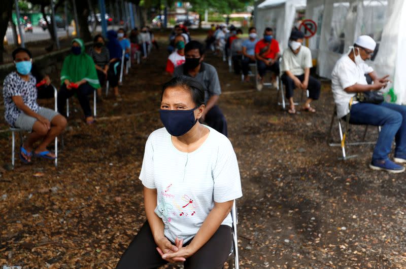 FILE PHOTO: People wearing protective face mask practice social distancing while receiving rice from an automated rice ATM distributor amid the coronavirus disease (COVID-19) spread in Jakarta