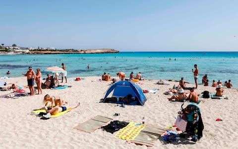 Tourists relax on the beach in Ayia Napa - Credit: Amir MAKAR / AFP