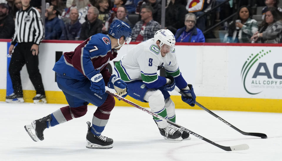 Vancouver Canucks center J.T. Miller, right, drives past Colorado Avalanche defenseman Devon Toews on the way to scoring a goal during the second period of an NHL hockey game Wednesday, Nov. 22, 2023, in Denver. (AP Photo/David Zalubowski)