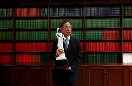 FILE PHOTO: Barrister Martin Lee, 75, a former lawmaker and founding chairman of the Democratic Party, poses with a model of the Goddess of Democracy statue at his office in Hong Kong May 21, 2014. REUTERS/Bobby Yip/File Photo