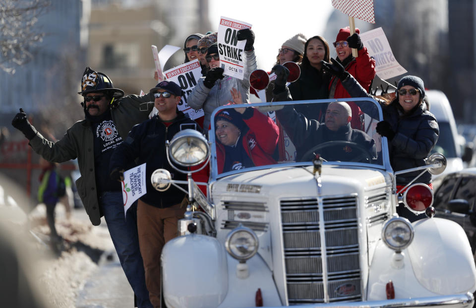 Denver teachers ride on the back of a vintage Denver Fire Department truck past a strike rally on the west steps of the State Capitol Monday, Feb. 11, 2019, in Denver. The strike is the first for teachers in Denver since 1994 and centers on base pay. (AP Photo/David Zalubowski)