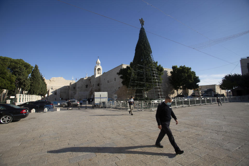 A man walks outside the Church of the Nativity, traditionally believed to be the birthplace of Jesus Christ, in the West Bank City of Bethlehem, Monday, Nov. 23, 2020. Normally packed with tourists from around the world at this time of year, Bethlehem resembles a ghost town – with hotels, restaurants and souvenir shops shuttered by the pandemic. (AP Photo/Majdi Mohammed)