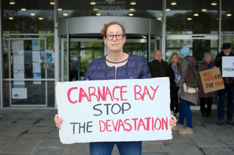 Gill Scott Anderson, of St Ives Climate Coalition, held up her sign behind hotel owner Stephen Baker as he addressed the planning committee