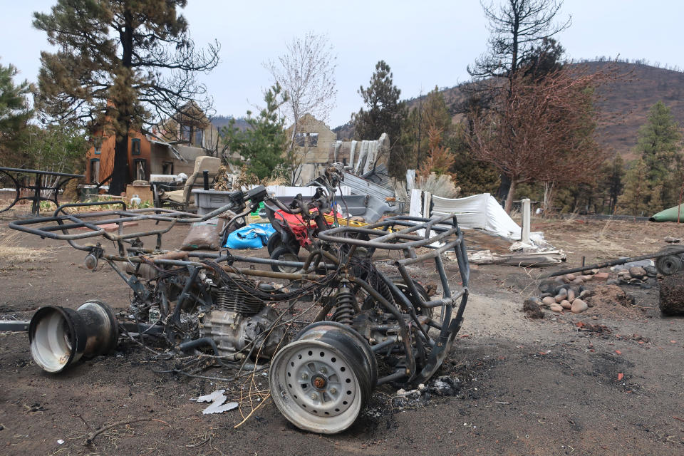 An all-terrain vehicle that was burned by a massive wildfire outside Flagstaff, Ariz., sits outside the home of Jeanne and Mike Welnick, Tuesday, April 26, 2022. The blaze that started Easter Sunday burned about 30 square miles and more than a dozen homes, hopscotching across the parched landscape. (AP Photo/Felicia Fonseca)