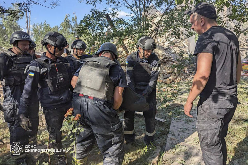 In this photo provided by the Ukrainian Emergency Service, emergency workers carry a body after a Russian missile hit the area, in Kryvyi Rih, Ukraine, Wednesday, June 12, 2024. (Ukrainian Emergency Service via AP)