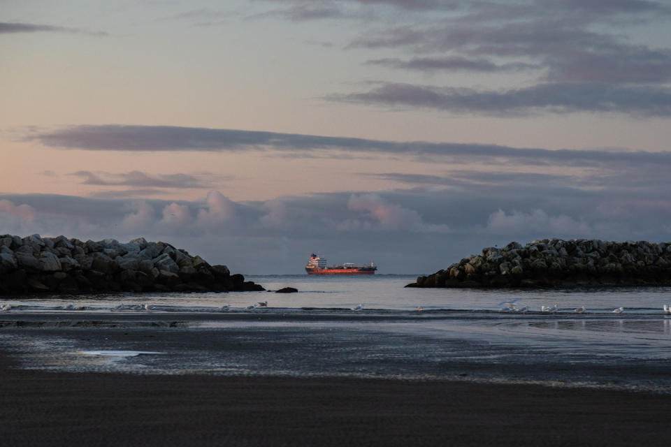 Sunrise illuminates a large ship off the coast of Nome, Alaska, viewed through a gap in the jetty of its existing port.<span class="copyright">Acacia Johnson for TIME</span>