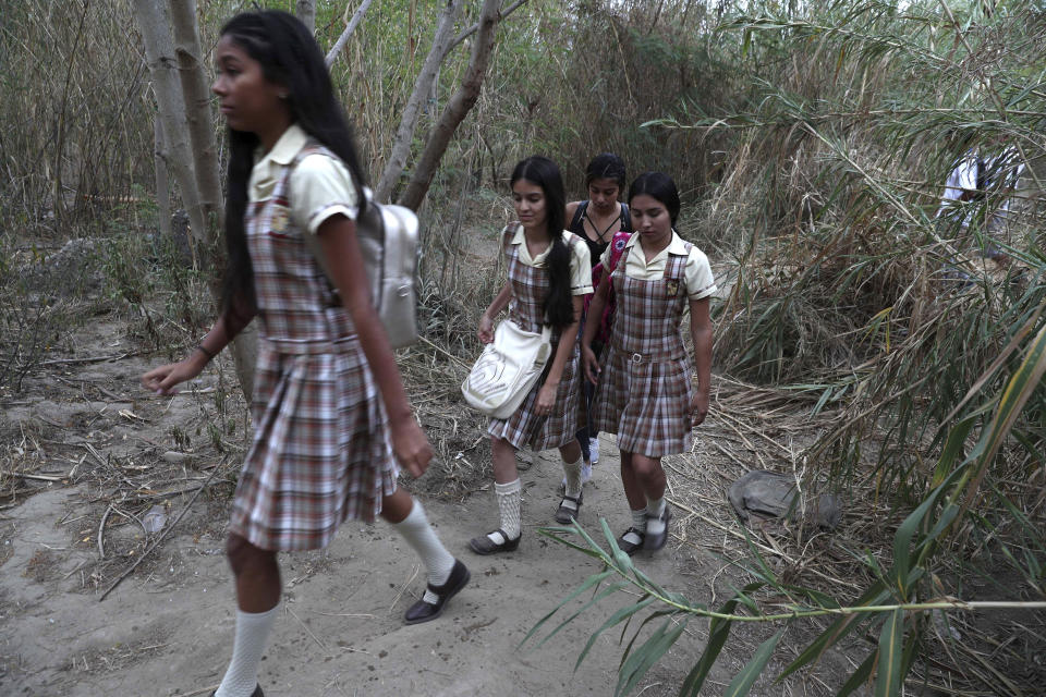 Varias estudiantes se dirigen a pie por una vereda a lo largo del río Táchira en el lado de Venezuela para ir a la escuela en Colombia, cerca del Puente Internacional Francisco de Paula Santander, el miércoles 6 de marzo de 2019. (AP Foto/Martín Mejia)