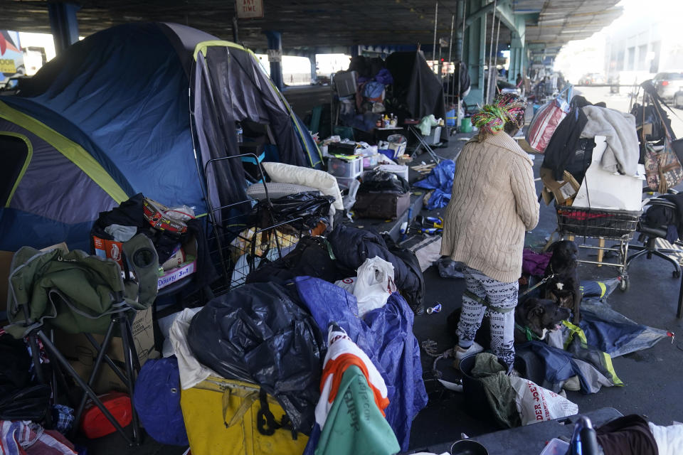 A woman gathers possessions to take before a homeless encampment was cleaned up in San Francisco, Tuesday, Aug. 29, 2023. Cities across the U.S. are struggling with and cracking down on tent encampments as the number of homeless people grows, largely due to a lack of affordable housing. Homeless people and their advocates say sweeps are cruel and costly, and there aren't enough homes or beds for everyone. (AP Photo/Jeff Chiu)