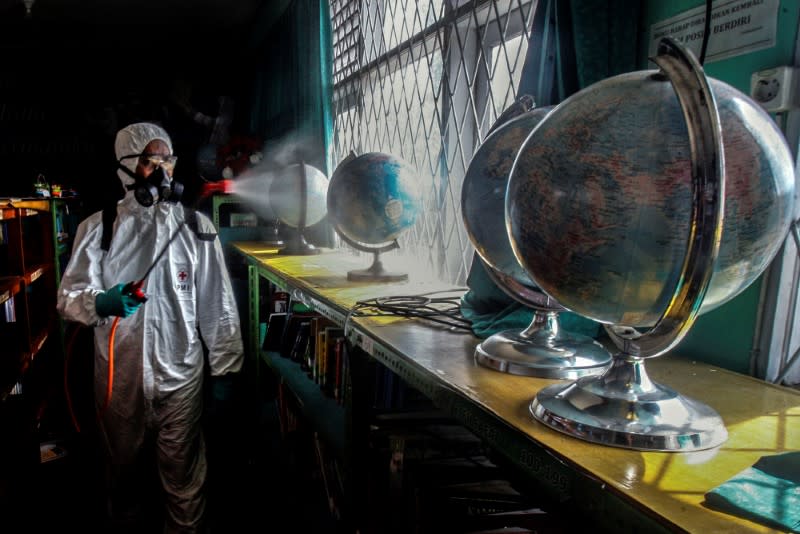 A worker sprays disinfectant at school to prevent the spread of coronavirus disease (COVID-19) in Bogor, near Jakarta