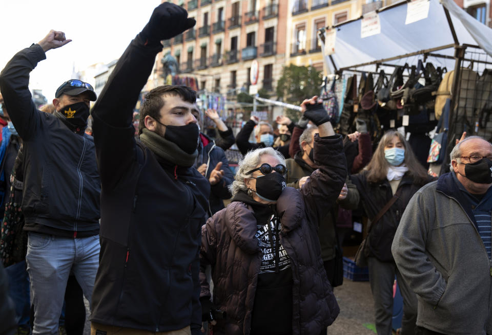 People protest restrictions imposed by authorities due to the pandemic in the Rastro flea market in Madrid, Spain, Sunday, Nov. 22, 2020. Madrid's ancient and emblematic Rastro flea market reopened Sunday after a contentious eight-month closure because of the COVID-19 pandemic that has walloped the Spanish capital. (AP Photo/Paul White)