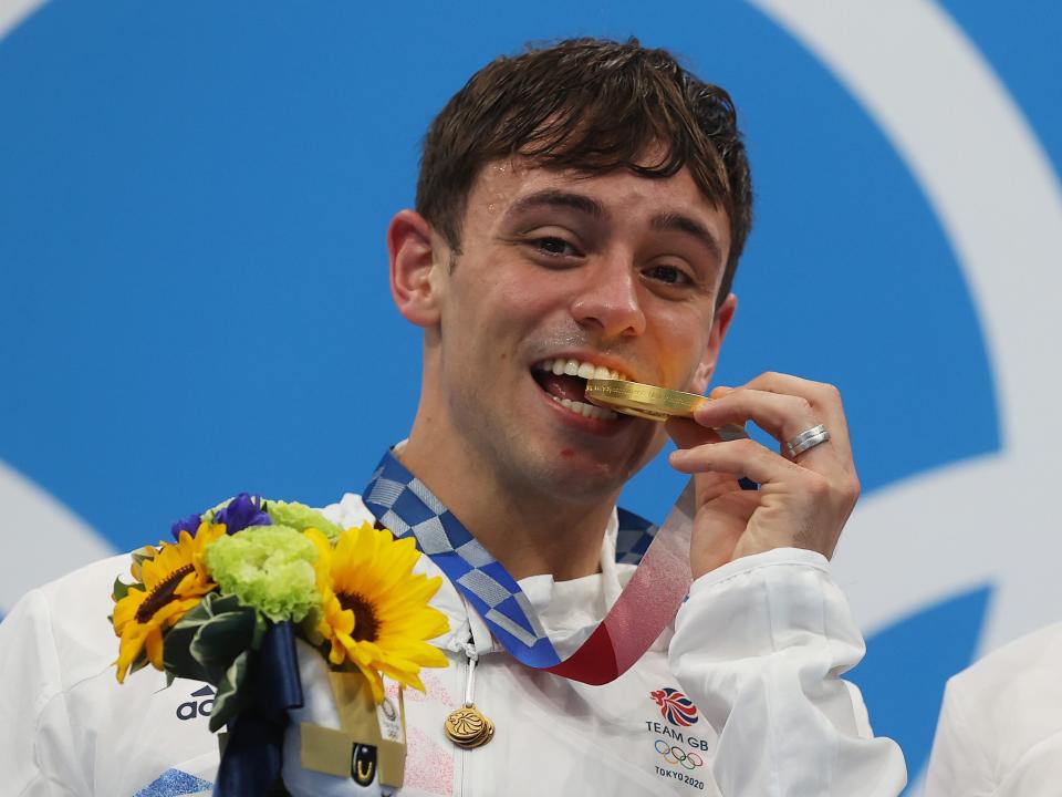 British diver Tom Daley biting his Tokyo Olympic gold medal