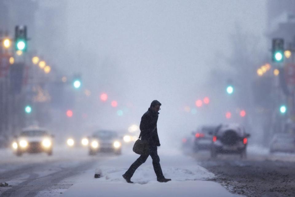 A man crosses Broad Street during a winter snowstorm Tuesday, Jan. 21, 2014, in Philadelphia. A swirling storm with the potential for more than a foot of snow clobbered the mid-Atlantic and the urban Northeast on Tuesday, grounding thousands of flights, closing government offices in the nation's capital and making a mess of the evening commute. (AP Photo/Matt Rourke)