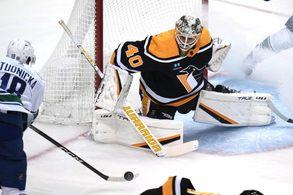 Vancouver Canucks' Jack Studnicka (18) gets a shot off in front of Pittsburgh Penguins goaltender Dustin Tokarski (40) during the first period of an NHL hockey game in Pittsburgh, Tuesday, Jan. 10, 2023. (AP Photo/Gene J. Puskar)