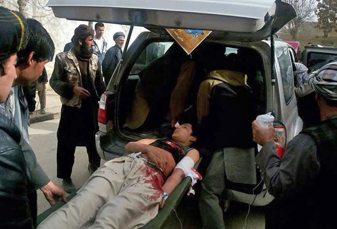 In this image taken with a mobile phone, Afghans help an injured man into a vehicle after a suicide attack in Maymana, capital of Faryab province, Afghanistan, Tuesday, March 18, 2014. A suicide bomber riding a rickshaw blew himself up outside a checkpoint at a market in northern Afghanistan on Tuesday, killing at least 13 civilians, officials said, in the latest attack in the countdown to presidential elections to be held in less than three weeks. (AP Photo)