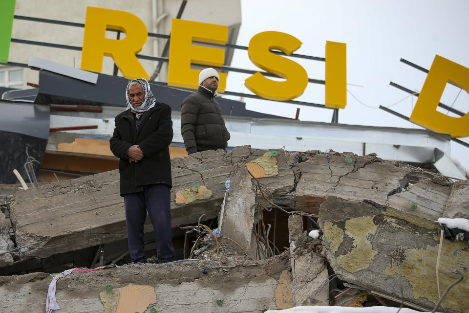 A man prays on a collapsed building in Malatya, Turkey, Tuesday, Feb. 7, 2023. Search teams and aid are pouring into Turkey and Syria as rescuers working in freezing temperatures dig through the remains of buildings flattened by a magnitude 7.8 earthquake. (AP Photo/Emrah Gurel)