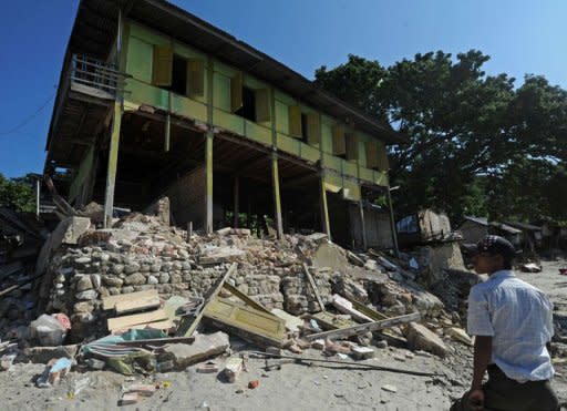 Maynmar villagers walk past an earthquake damaged house in Thabeik Kyin township, Mandalay. The quake has left 38 people dead or missing, the Red Cross said as a new tremor rattled the government's capital Naypyidaw