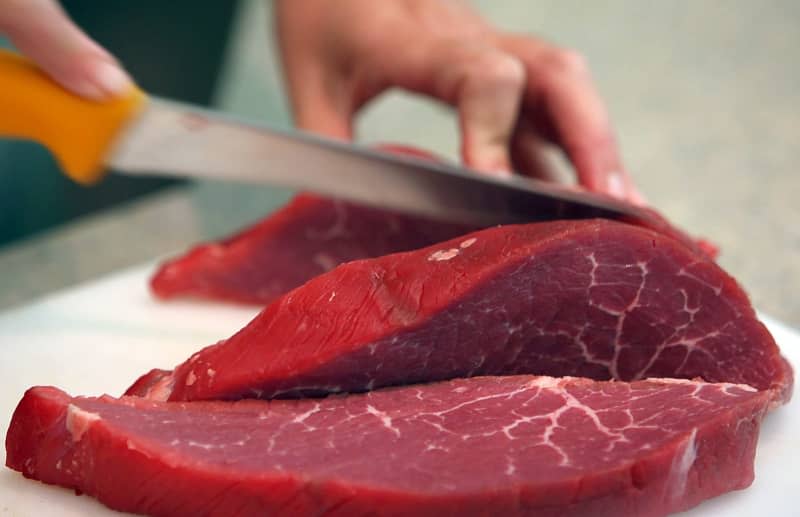 A Butches slices a piece of Beef. European food trade unions called for better working conditions for workers in the bloc's meat sector during a conference held in Berlin on Tuesday. Oliver Berg/dpa