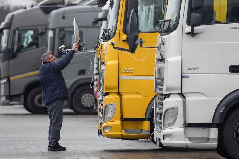 A Hungarian truck driver adjusts a satellite dish for viewing television on the front of his lorry whilst he waits at Ashford International Truck Stop, in Ashford