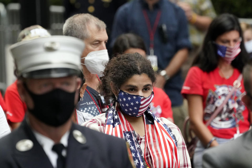 A woman wearing a flag mask joins others in prayer at the Tunnel to Towers ceremony, Sept. 11, 2020, in New York. Vice President Mike Pence and his wife Karen will attend the ceremony where the names of nearly 3,000 victims of the Sept. 11, 2001 terror attacks will be read by family members. (AP Photo/Mark Lennihan)