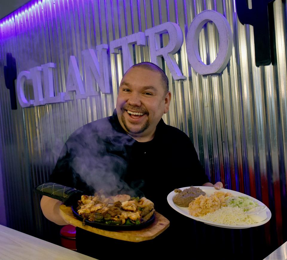Cilantro Mexican Restaurant owner Miguel Angel is all smiles as he holds Trio Fajitas,  chicken, shrimp and steak with onions and peppers served on a sizzling platter at 388 E. Monroe St. in Dundee.