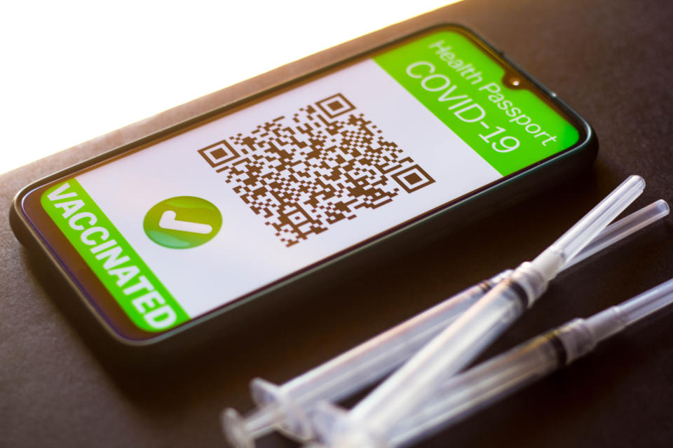 BRAZIL - 2021/04/05: In this photo illustration a symbolic COVID-19 health passport seen on a smartphone screen next to the medical syringes. (Photo Illustration by Rafael Henrique/SOPA Images/LightRocket via Getty Images)