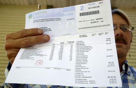 Dan Koivisto poses with a copy of his 2013 property tax bill at his home in Ingleside, Illinois, United States, July 30, 2015. REUTERS/Jim Young