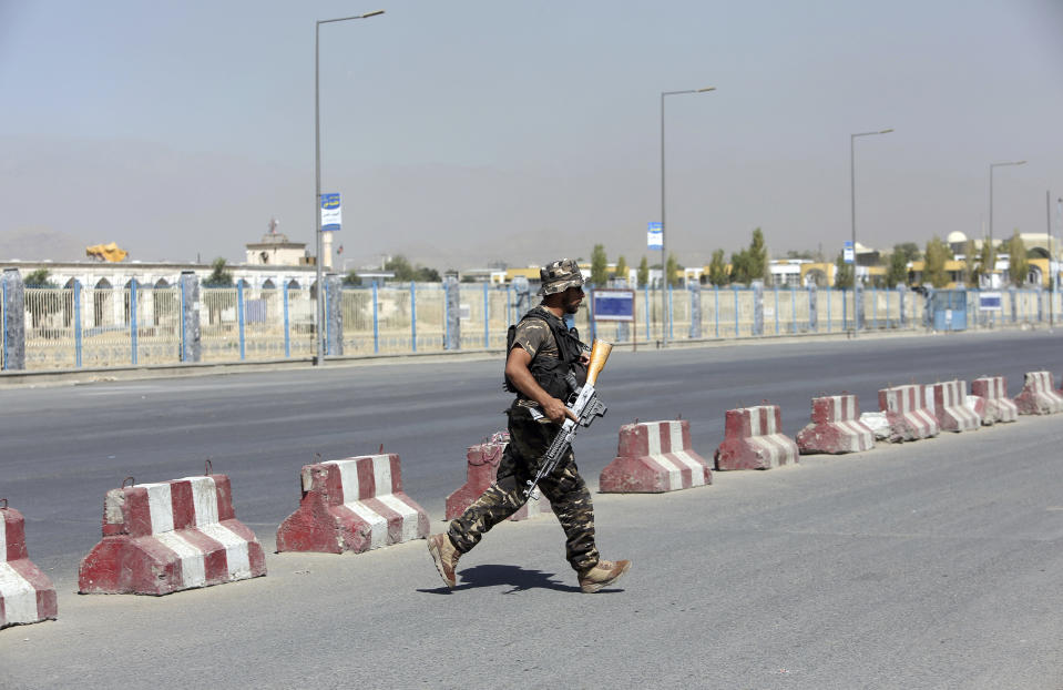 An Afghan security officer runs toward a house where attackers are hiding, in Kabul, Afghanistan, Tuesday, Aug. 21, 2018. Afghan police say the Taliban fired rockets toward the presidential palace in Kabul as President Ashraf Ghani was giving his holiday message for the Muslim celebrations of Eid al-Adha. (AP Photo/Rahmat Gul)