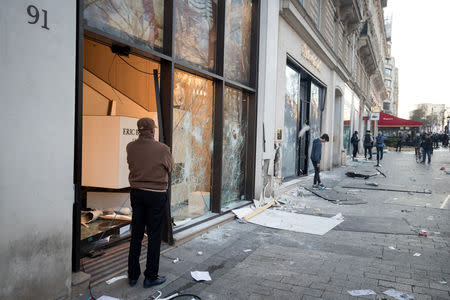 A man stand in front of a damaged and looted shop on the Champs Elysees avenue during a demonstration by the "yellow vests" movement in Paris, France, March 16, 2019. Picture taken March 16, 2019. REUTERS/Philippe Wojazer