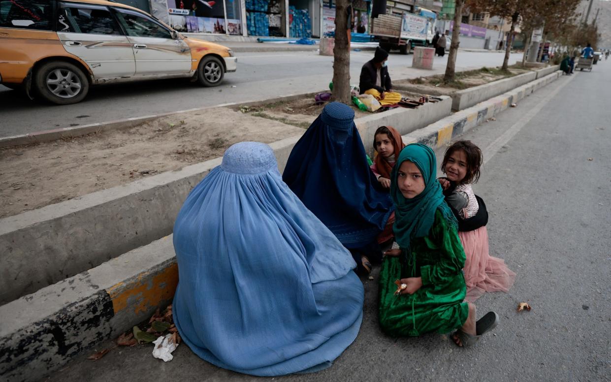 Women wearing burqas sit with their children as the beg along a road in Kabul, Afghanistan October 26, 2021. REUTERS/Zohra Bensemra