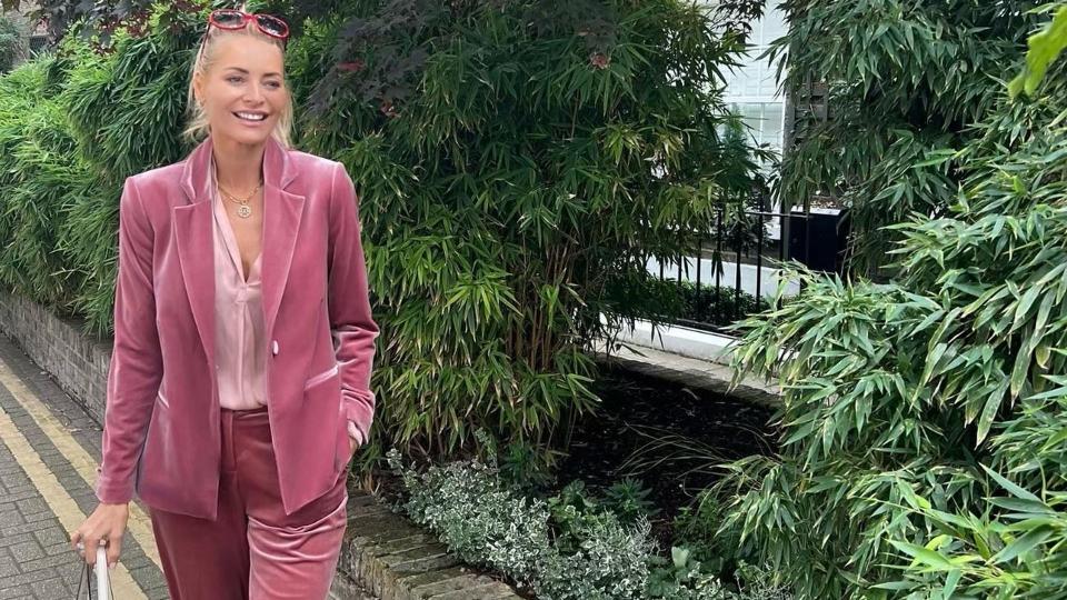 Tess in a pink velvet suit against trees